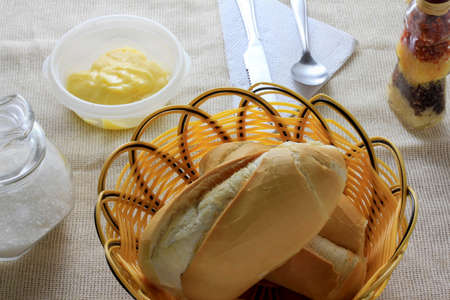 close up french bread on breakfast table with butter and cutlery, top view