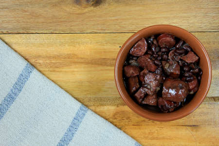 pot with feijoada, traditional brazilian cuisine dish, isolated under wooden background, top viewの写真素材