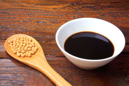 Soy beans with dark soy sauce in a ceramic bowl on rustic wooden tableの写真素材