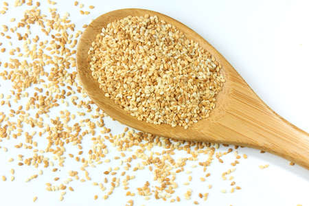 Sesame seeds in wooden spoon isolated on white background, top view. macro photographyの写真素材