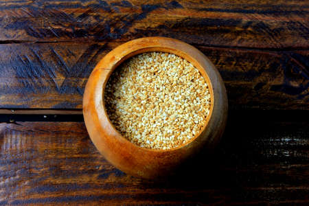 Sesame seeds in wooden bowl isolated on background rustic wooden table, top view.の写真素材