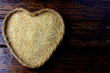 Sesame seeds in basket with heart shape isolated on rustic wooden table, top view.の写真素材