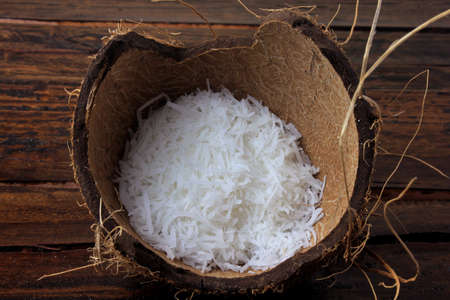 fresh coconut flakes and chips placed in bark and shell isolated on rustic wooden backgroundの写真素材