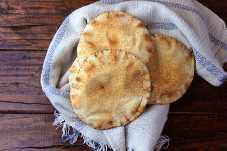 Pita bread isolated on rustic wooden table on rustic cloth. Traditional and typical food of Arabic...