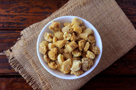 pork rinds (torresmo) fried in ceramic bowl on rustic wooden table in restaurant. typical dish of Brazilian and Asian cuisineの写真素材