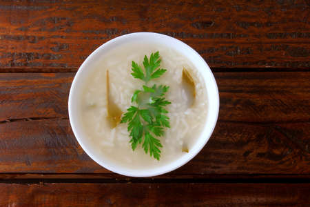 congee in ceramic bowl on rustic wooden table, traditional rice porridge typical of Asian cuisine. Top viewの写真素材