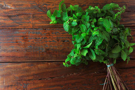 Group of fresh organic green mint on rustic wooden table. Aromatic peppermint with medicinal and culinary uses. top viewの写真素材