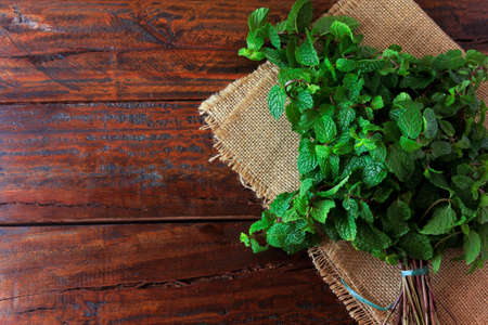 Group of fresh organic green mint on rustic wooden table. Aromatic peppermint with medicinal and culinary uses. top viewの写真素材