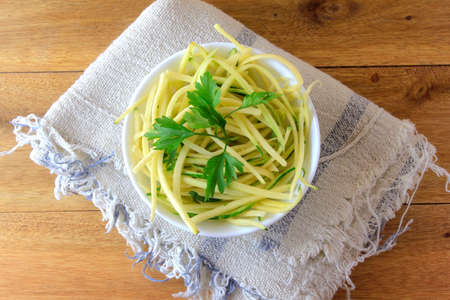 Homemade raw zucchini pasta in ceramic bowl on rustic wooden table. concept of healthy food. Top viewの写真素材