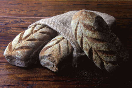 Australian bread inside rustic bag over rustic wooden background. Traditionally this bread is made with chocolate powder, brown sugar and honey. front viewの写真素材