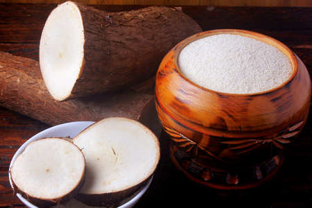cassava flour (farinha de mandioca) in wooden bowl on rustic table. chopped manioc sliced. food typical of brazilian cuisineの写真素材