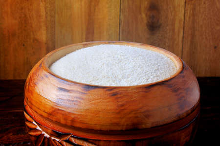 cassava flour (farinha de mandioca) in wooden bowl isolated on rustic table. food typical of brazilian cuisineの写真素材