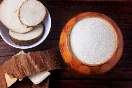 cassava flour (farinha de mandioca) in wooden bowl on rustic table. chopped manioc sliced. food typical of brazilian cuisineの写真素材