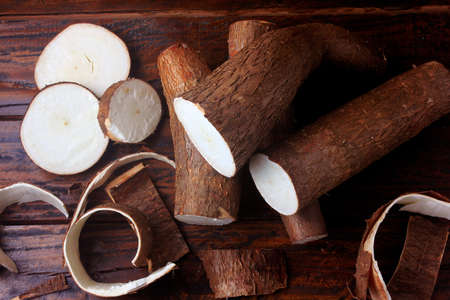 fresh cassava and peels and slices on rustic wooden table. Top viewの写真素材