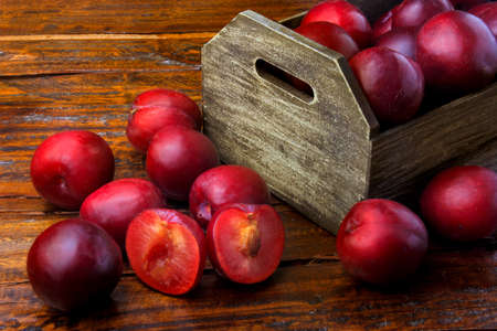 raw and fresh organic plums inside rustic fabric wooden box on rustic table. Close-up viewの写真素材