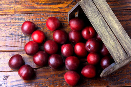 raw and fresh organic plums inside rustic fabric wooden box on rustic table. Close-up viewの写真素材