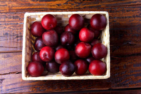 raw and fresh organic plums inside rustic fabric wooden box on rustic table. Close-up viewの写真素材