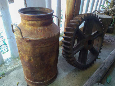vintage and antique milk brass on rustic farmhouse porch next to watermill gearの写真素材