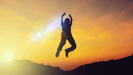 Silhouette of a young man jumping on background with sunset. front viewの写真素材