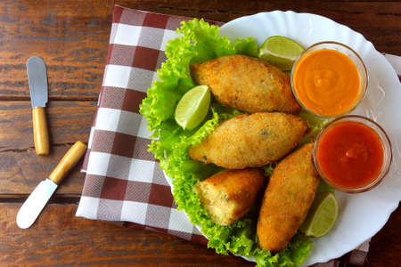 salt cod fritter, bacalao bunuelos over rustic wooden restaurant table. Codfish balls top view.