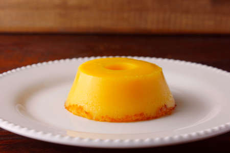 Quindim is a sweet that has as ingredients egg yolk, sugar and grated coconut, very traditional in Brazil, on wood rustic tableの写真素材