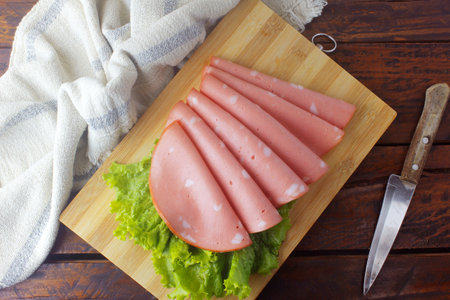 sliced mortadella on cutting board in kitchen with rustic table. Italian food