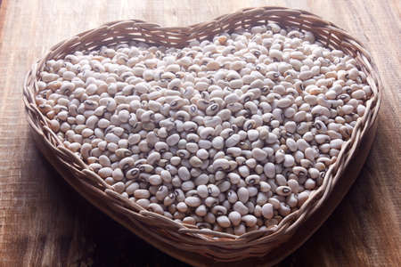 Raw grains fradinho beans in rustic basket on wooden table. Top viewの写真素材
