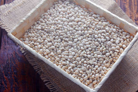 Raw grains fradinho beans in rustic basket on wooden table. Top view
