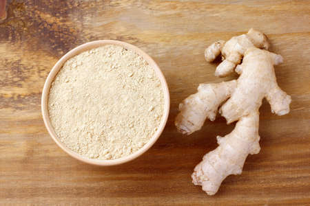 Ground ginger powder in ceramic bowl over rustic wooden table. Anti-inflammatory and antioxidantの写真素材