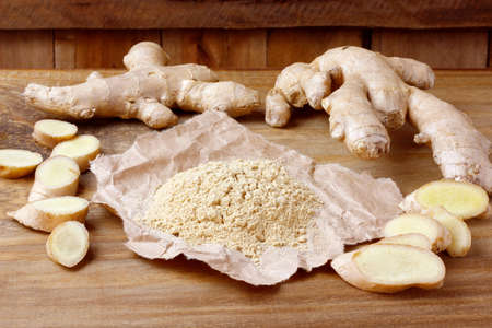 Ground ginger powder on paper over rustic wooden table. Anti-inflammatory and antioxidant