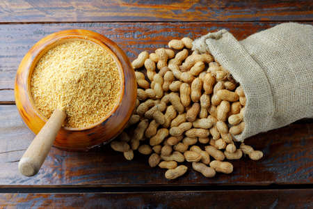 Crushed and ground peanuts in the wooden bowl forming a flour ingredient for the peanut butter and...