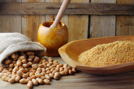 Crushed and ground peanuts in the wooden bowl forming a flour ingredient for the peanut butter and...