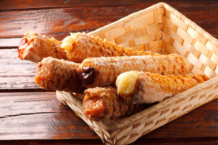 Homemade churros with multiple fillings in a basket on a rustic wooden table. top viewの写真素材