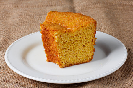 corn cake on white plate on rustic wooden table. Typical Brazilian party food. Selective focus