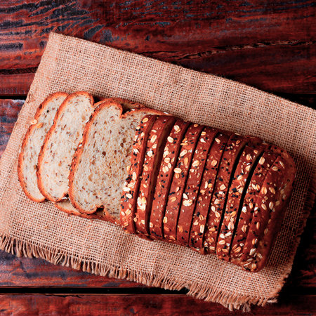 sliced whole wheat bread made with grains and seeds on a rustic wooden table. Close up