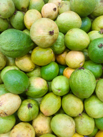 A pile of guavas stacked on a supermarket shelf. tropical fruits