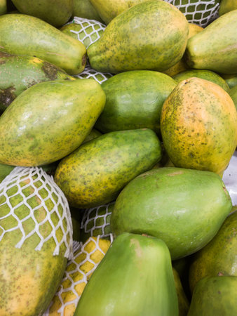 Fresh papayas stacked on a market stall. Tropical fruit display.の写真素材