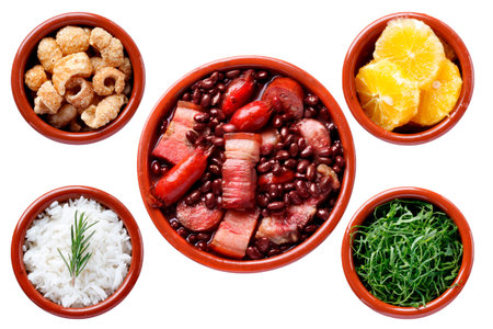 Traditional Brazilian feijoada isolated on a white background, accompanied by white rice, sliced ââkale, orange, and pork crackling in clay bowls. Top viewの写真素材
