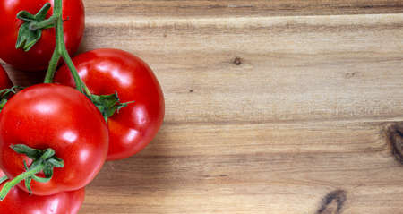 Red tomatoes on a wooden table surface