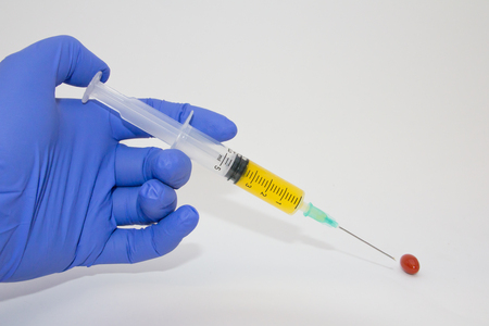 Close-up of a hand with a syringe and injecting liquid in a pill の写真素材