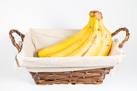 Studio shot of some bananas inside a basket の写真素材