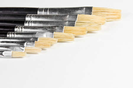 Close up of some paint brushes placed in diagonal row on white background の写真素材