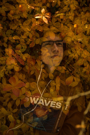 Portrait of a young man with glasses on the background of autumn leaves