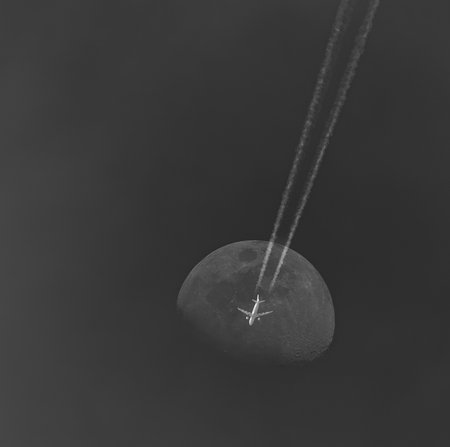 Airplane flying over the moon. Black and white image with copy space.の写真素材