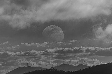 The full moon over the wind turbines in the mountains in black and whiteの写真素材