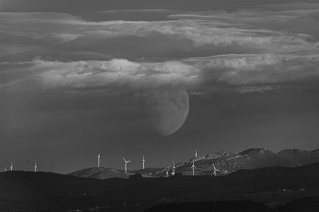 Wind turbines in the mountains at night with the moon in the skyの写真素材