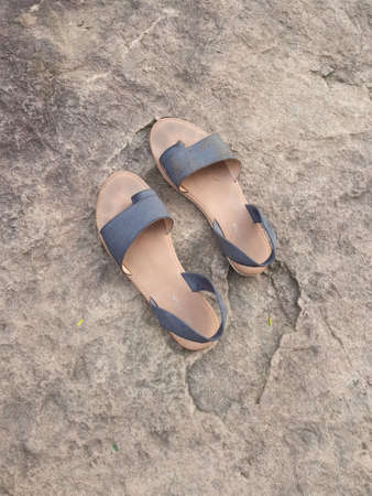 A pair of wet sandals on a big rock