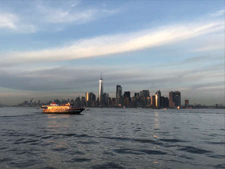 A sunset cruise to Ellis Island an Statue of Liberty. You can see the sun setting down and returns with all the lights shinning in New York City. Amazing landscape.の写真素材