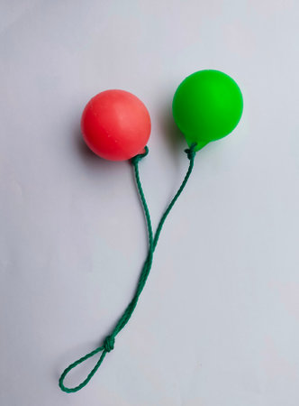 Two red and green balloons tied with a green rope on a white backgroundの写真素材