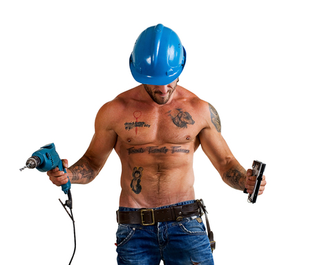 builder bodybuilder with tattoos making repairs with a drill on a white backgroundの写真素材